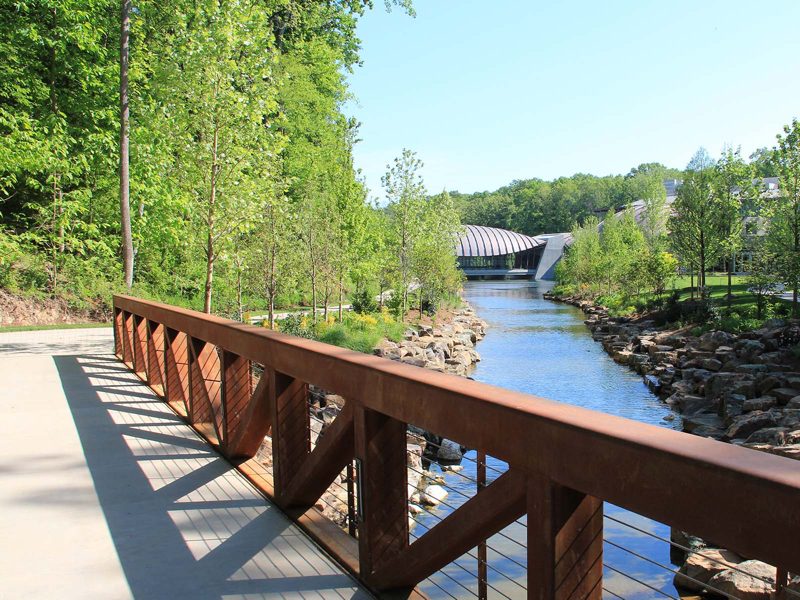 Paved trail along pond with museum building in background