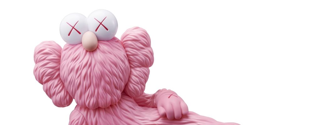 Escultura rosa de una figura recostada al estilo del artista KAWS.