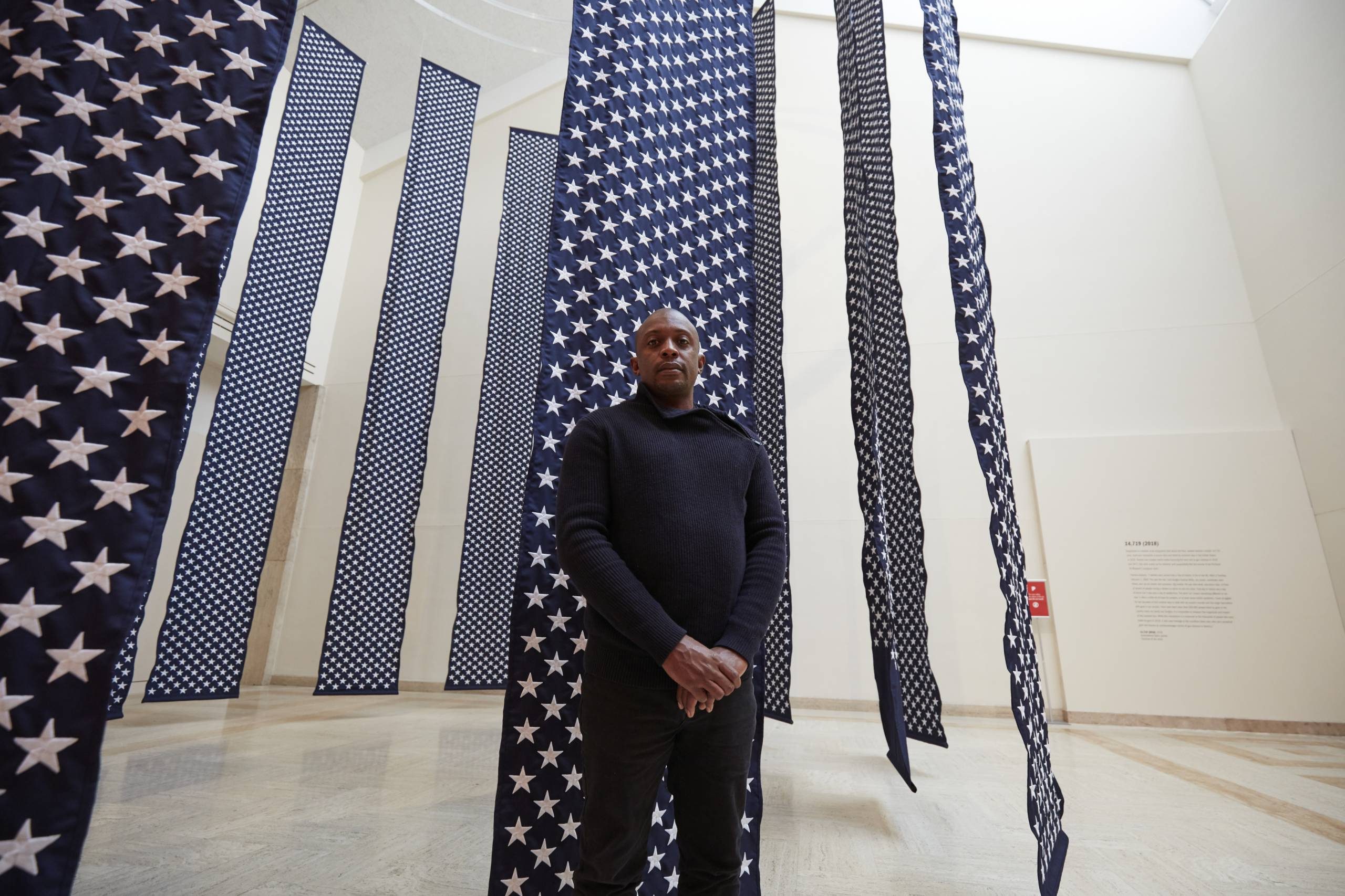 Person in gallery among star-patterned blue fabric panels, resembling the American flag.