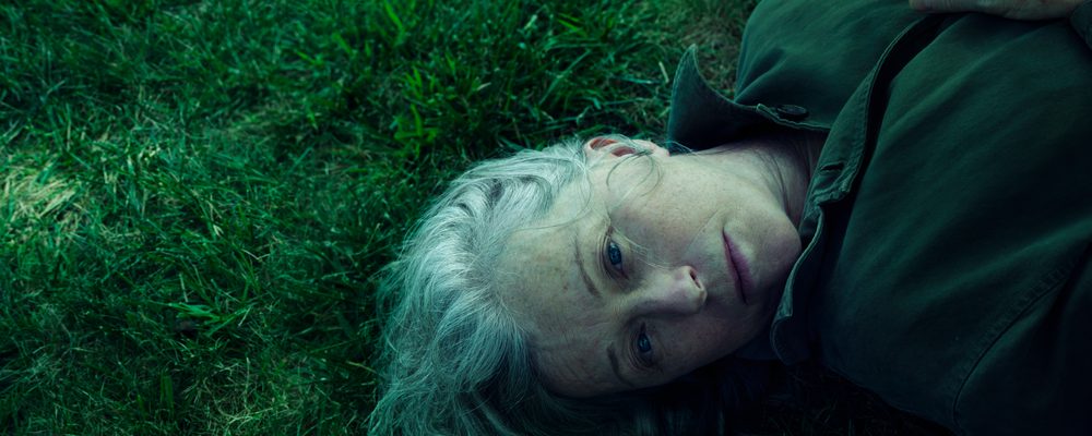 Headshot of an woman with gray hair laying in green grass