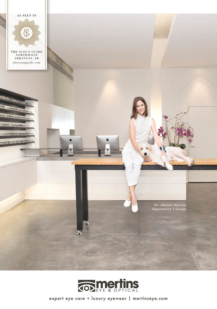 a woman dressed in white sits on a desk with a dog