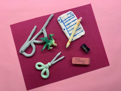 image of a collage portrait art activity with clay; this image features several clay objects based on items found in a backpack like paper and scissors