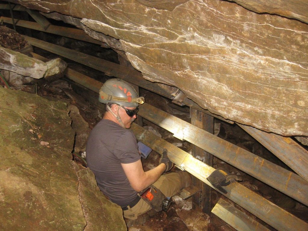 a man installing a steel gate in a bat cave to protect its entrance