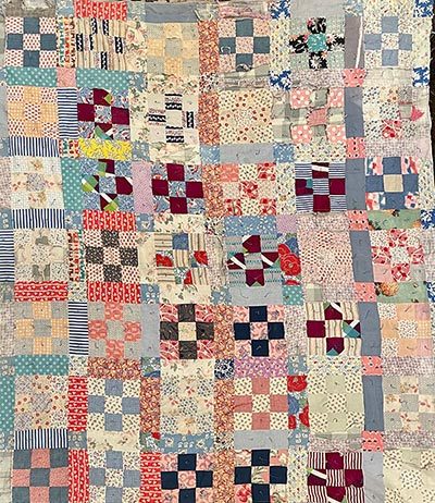 Handmade patchwork quilt with colorful fabric squares, floral, striped, checkered motifs.