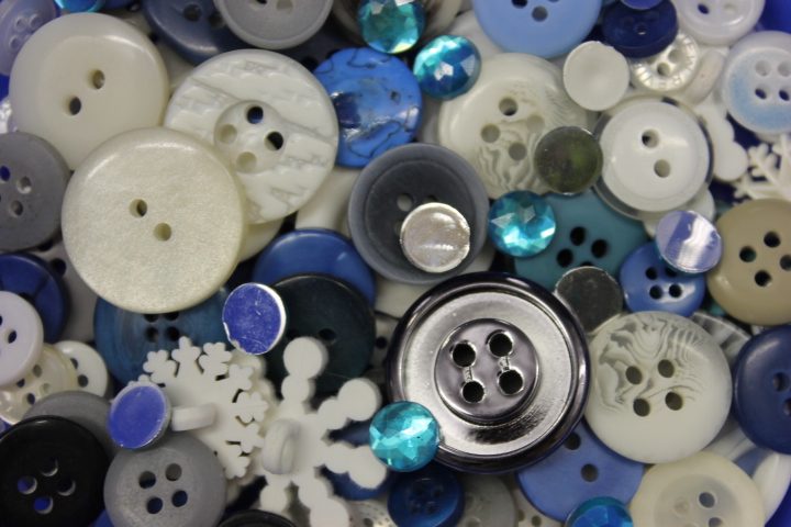 Assorted buttons in blue, white, and gray with occasional blue gemstones.