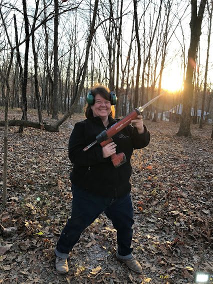 Staff member poses outdoors with a caulk gun
