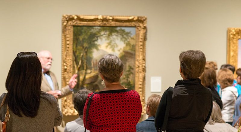 Art gallery group tour observing a scenic landscape painting.