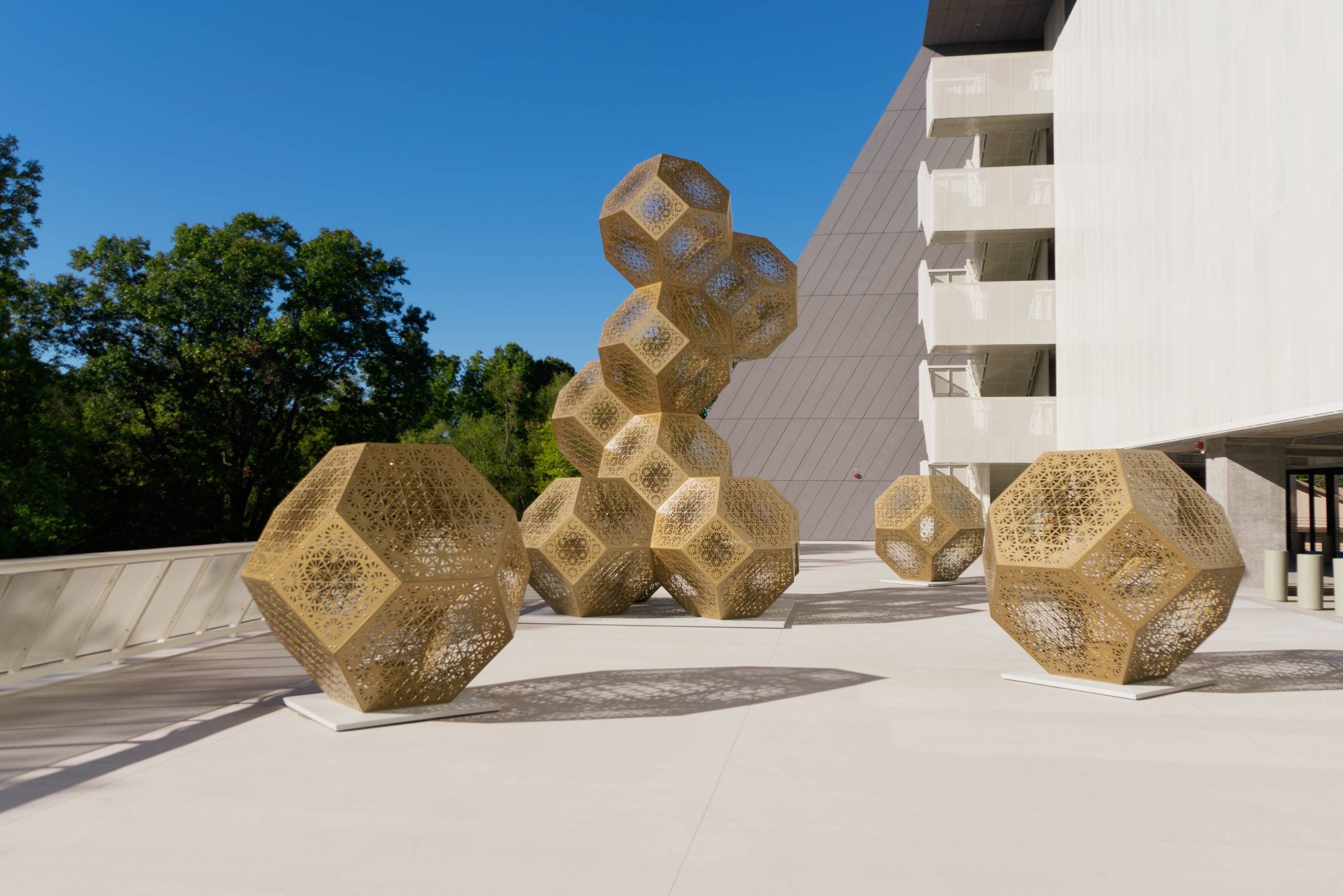 Outdoor installation with geometric metal sculptures on concrete near a modern building.