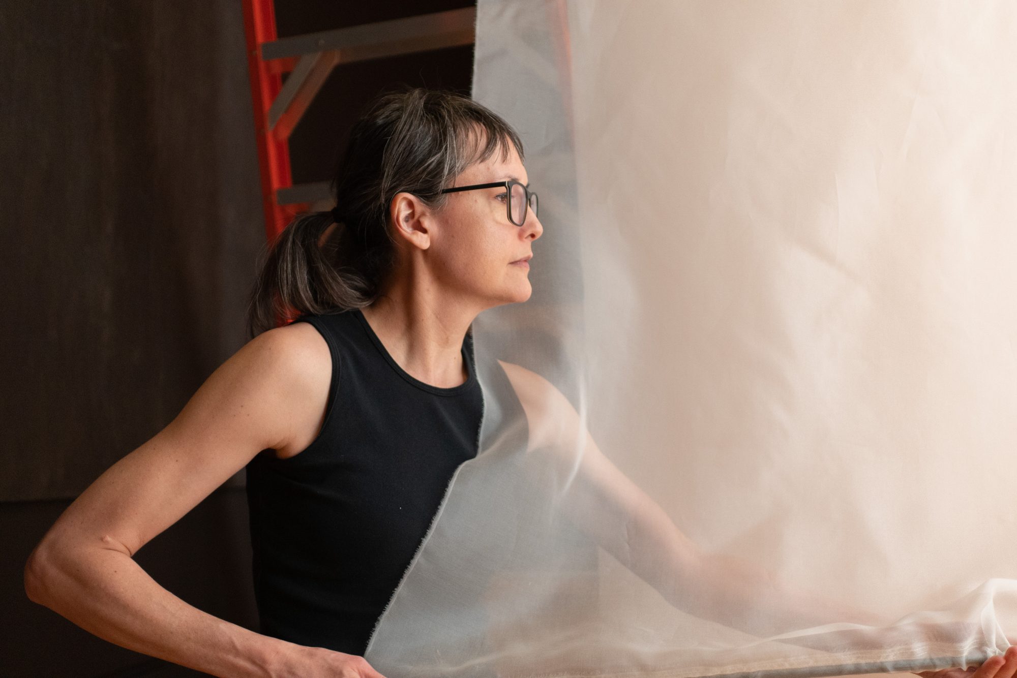 Artist threads a pipe through fabric banner