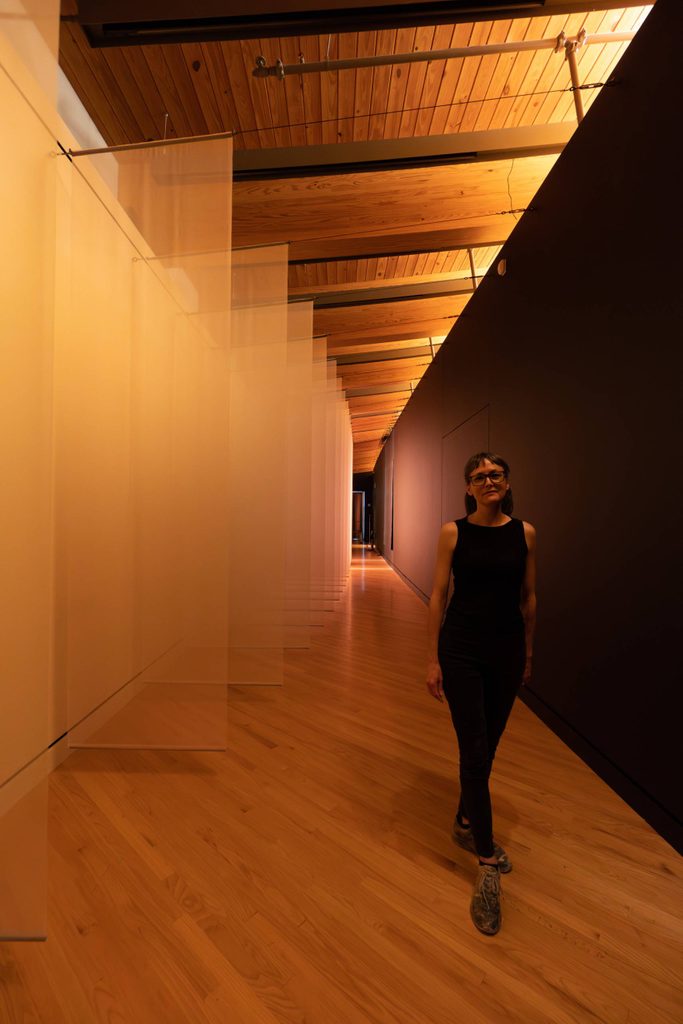 Woman stands beside row of fabric banners hanging from wall