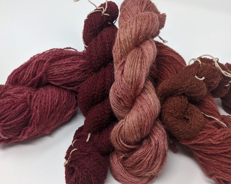 a pile of yarn in pink and burgundy hues