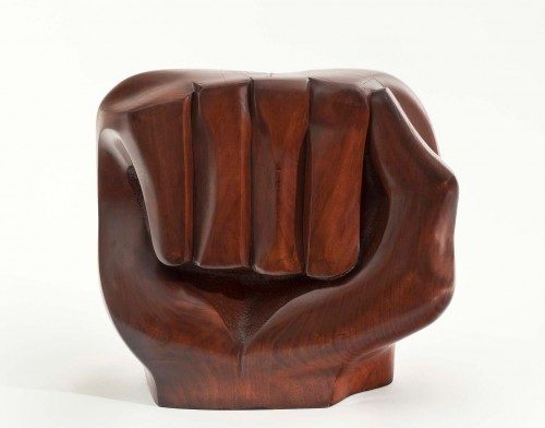 Wooden sculpture of a closed fist with smooth surfaces and natural wood grain patterns.