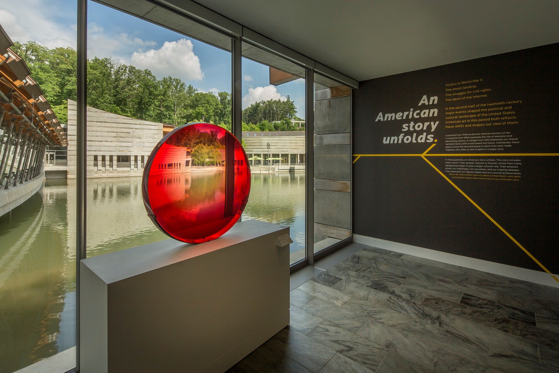 Interior with large windows, red glass sculpture, modern building, and American history text.