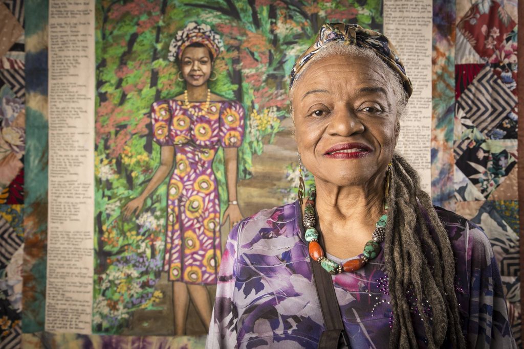 Artist Faith Ringgold poses in front of her artwork, Maya's Quilt of Life