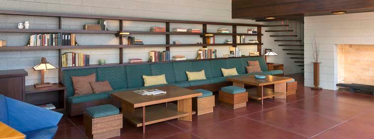 Spacious modern living room with bookshelf, cushioned seating, wooden furniture, and a fireplace.