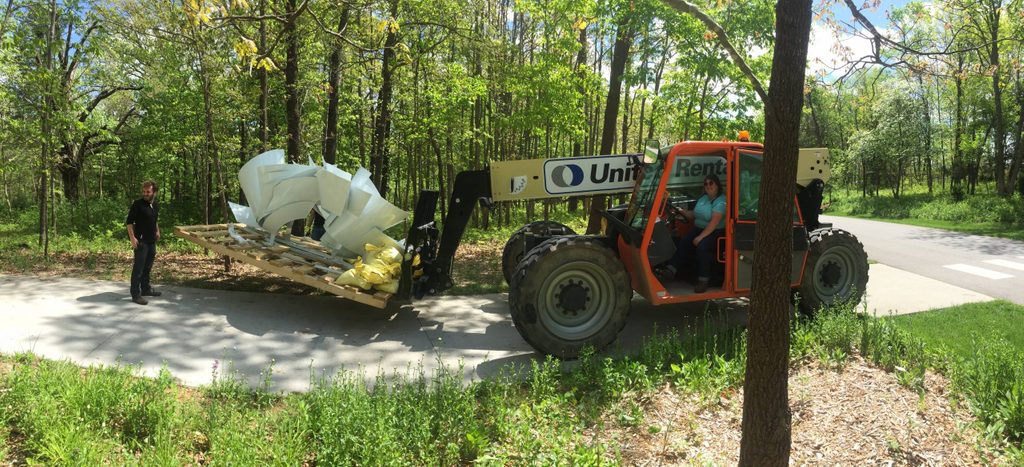 staff member rides a construction vehicle for installing outdoor artwork