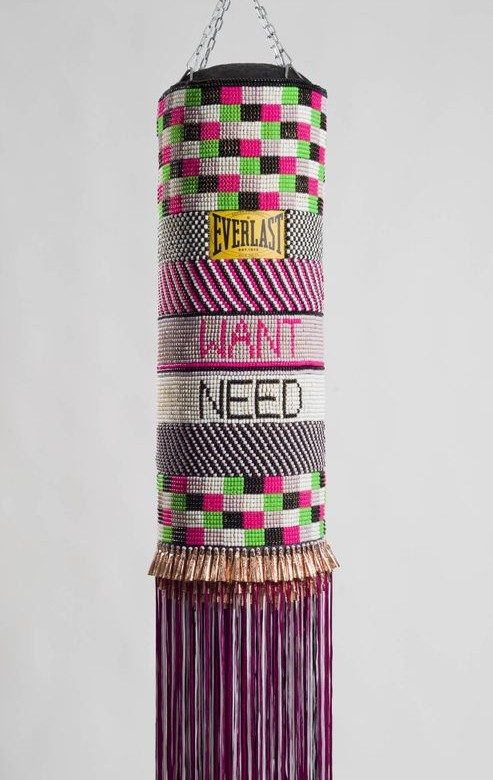 Hanging Everlast punching bag with colorful beadwork, geometric patterns, WANT and NEED text, and purple fringe.