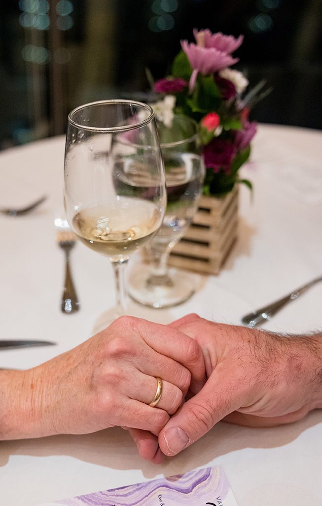 Couple holding hands with a glass of wine in the background