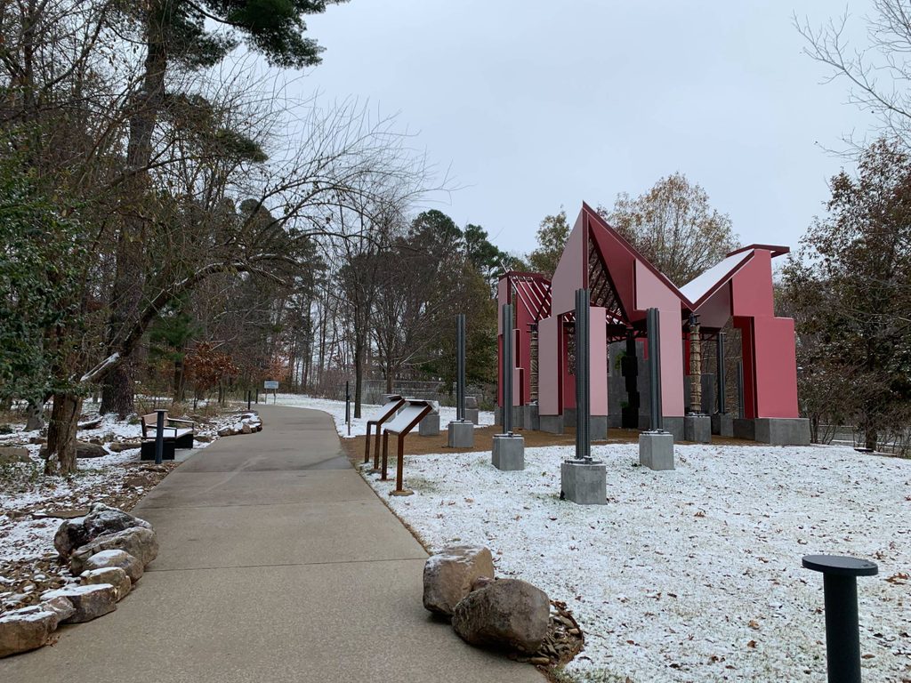 a pink and white architecture structure covered in snow sits next to a sidewalk path