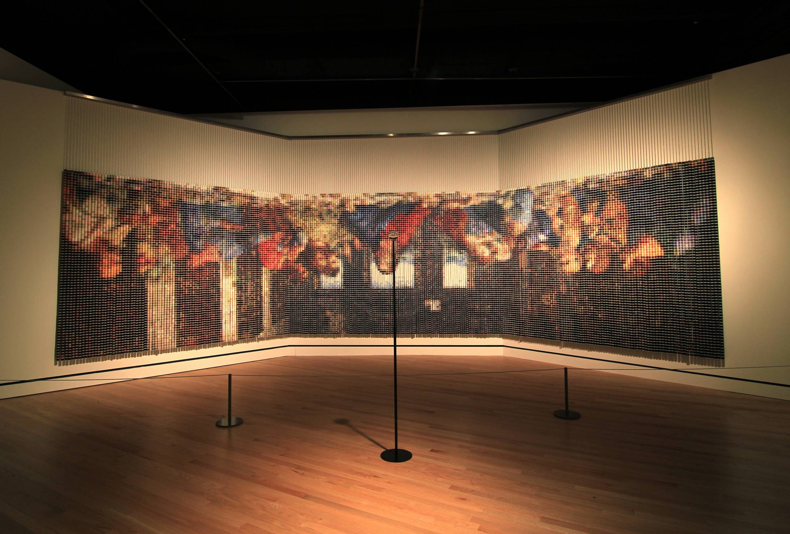 Art installation depicting The Last Supper using vertical hanging elements in a dim gallery.