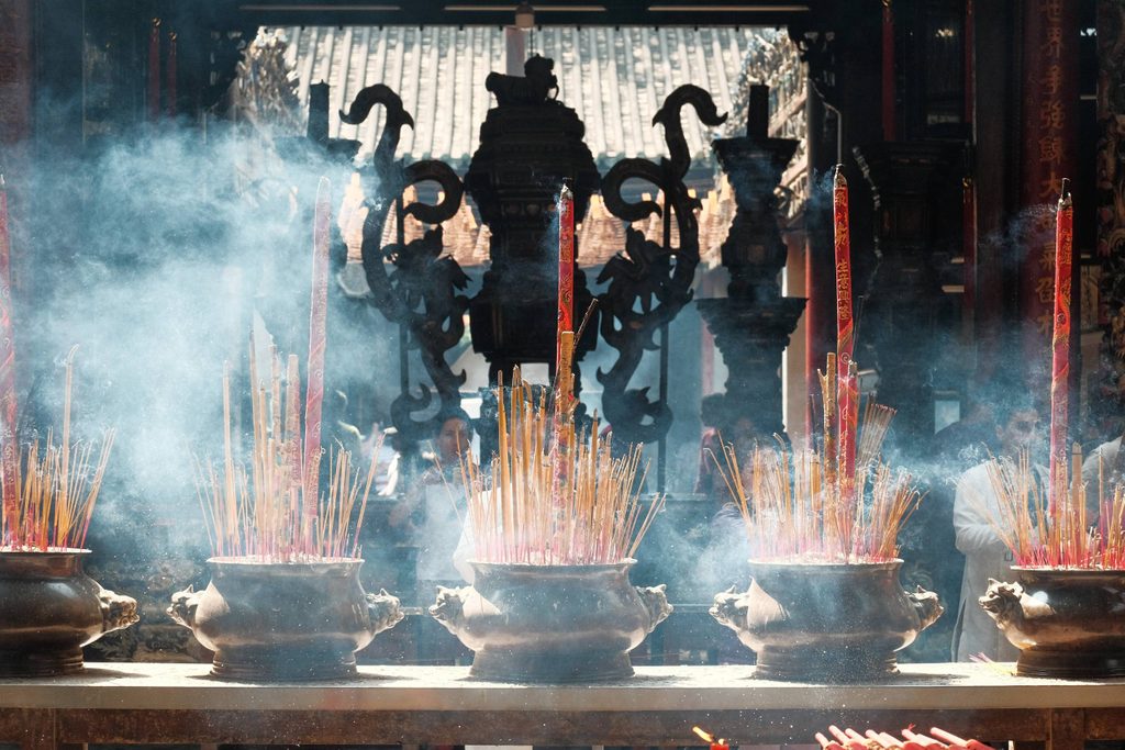 pots holding incense and candles inside a temple in asia