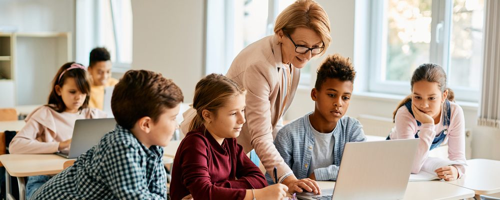 Elementary teacher and her students using laptop in class