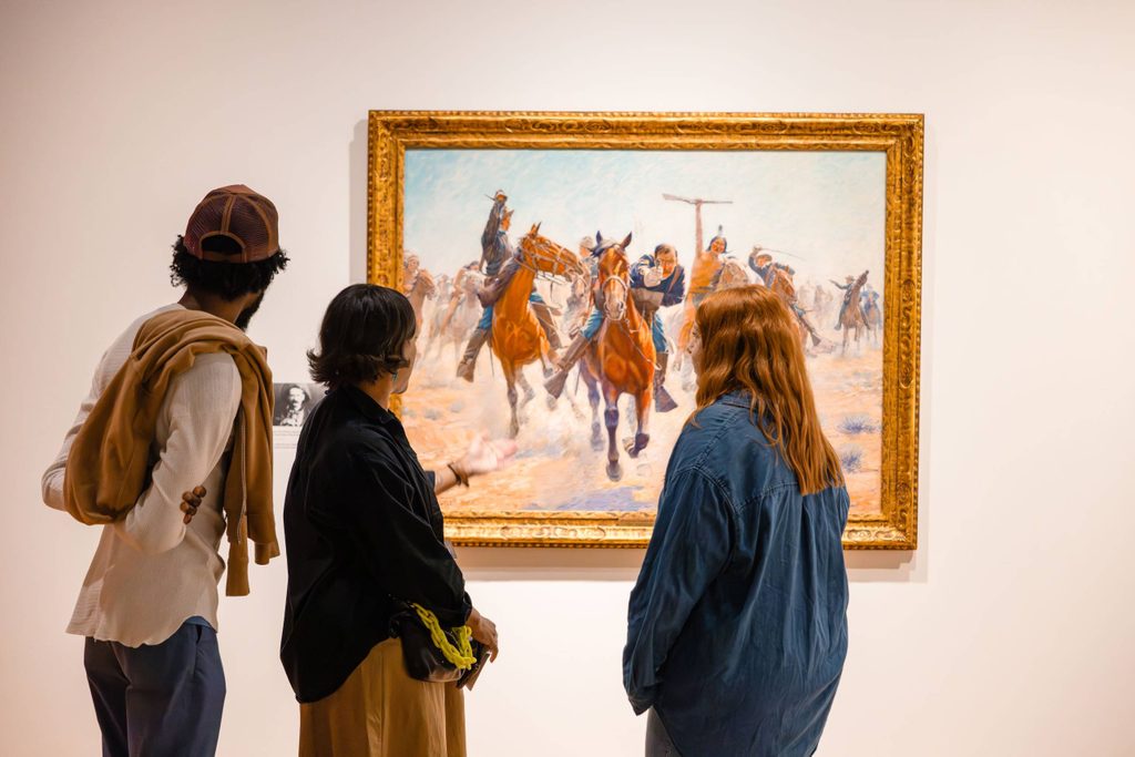 Three people view a work in 'Knowing the West' at Crystal Bridges.