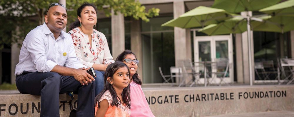 Family of four outside Foundgate Charitable Foundation, observing something together.