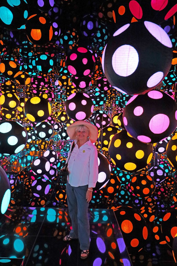 a woman visitor poses inside kusama's infinity mirrored room