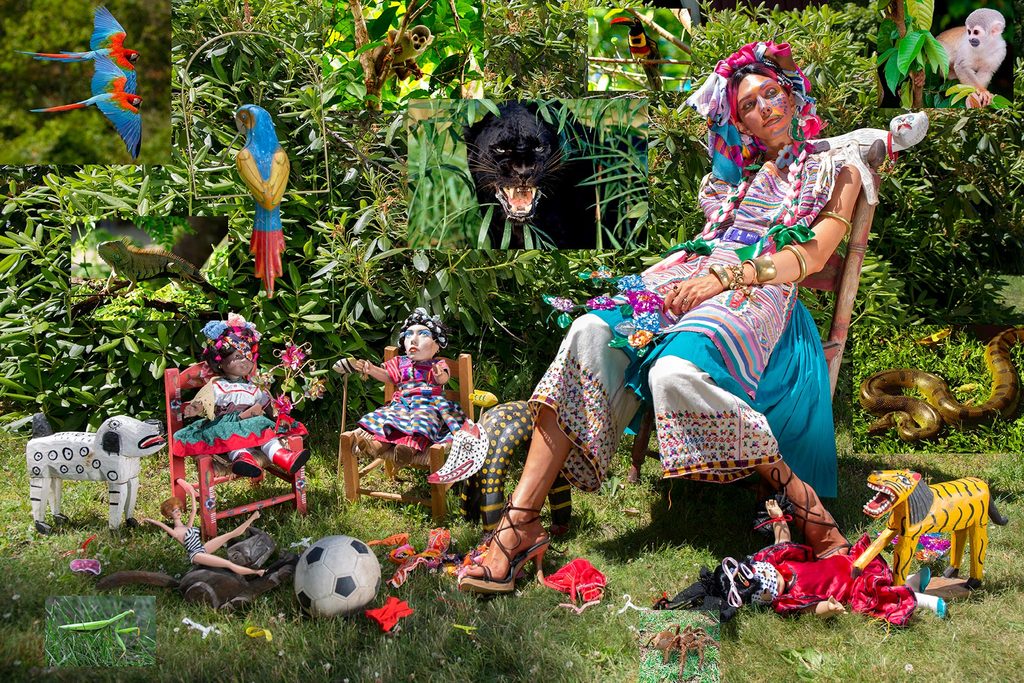 Woman in vibrant attire seated in tropical garden with animals, dolls, and colorful decorations.
