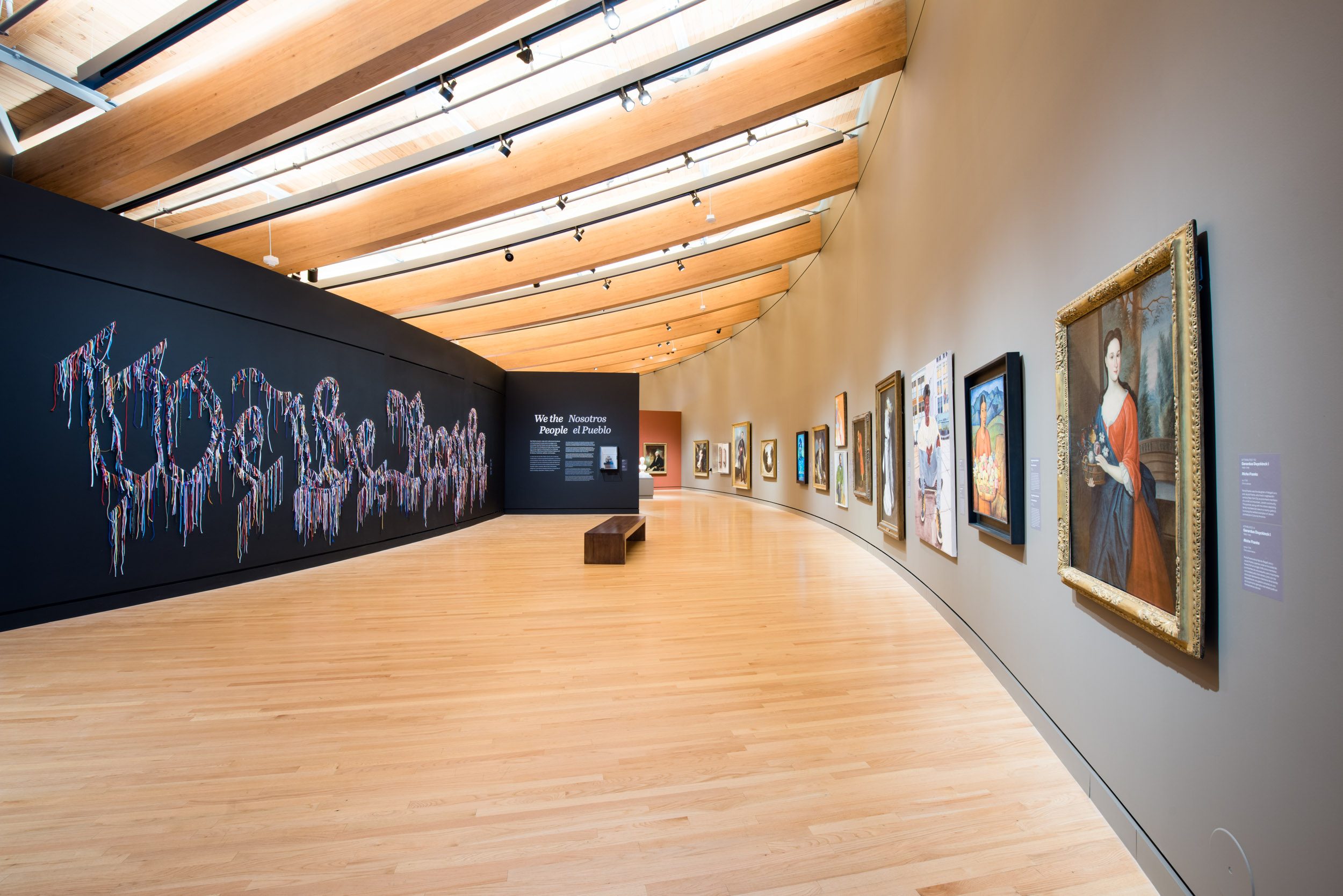 Art gallery with curved wood ceiling, framed paintings, and 