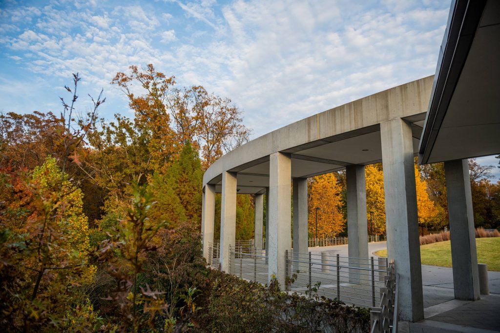 the museum's entrance columns framed by surrounding orange and brown trees in the fall