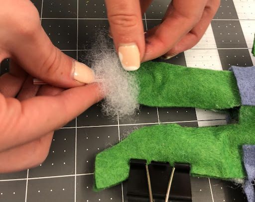 hands stuffing sewn felt to make a doll