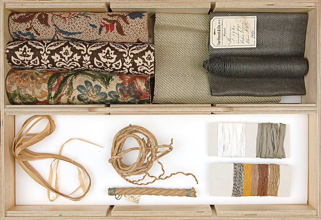 a collection of textiles and different colored strings in a wooden box