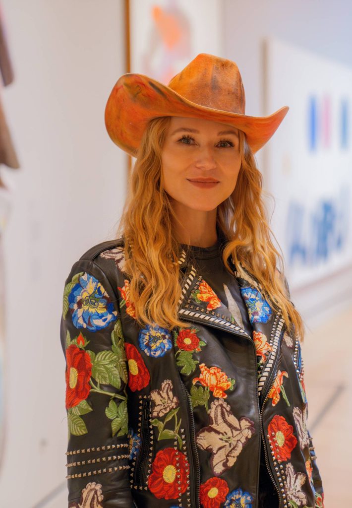Headshot of singer Jewel wearing a western hat and embroidered jacket in the Crystal Bridges gallery
