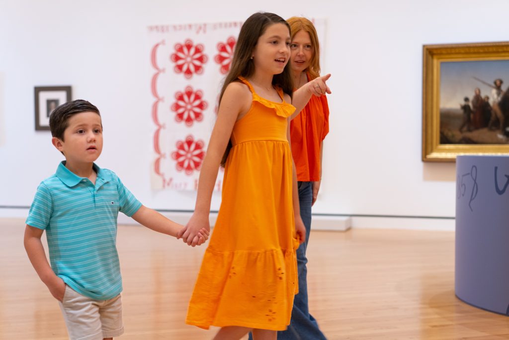 Woman and two children in an art gallery with various artworks on the walls.