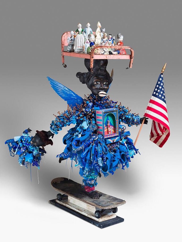 African-American doll wearing blue dress, riding a skateboard, while balancing a bed full of ceramic figurines on its head.