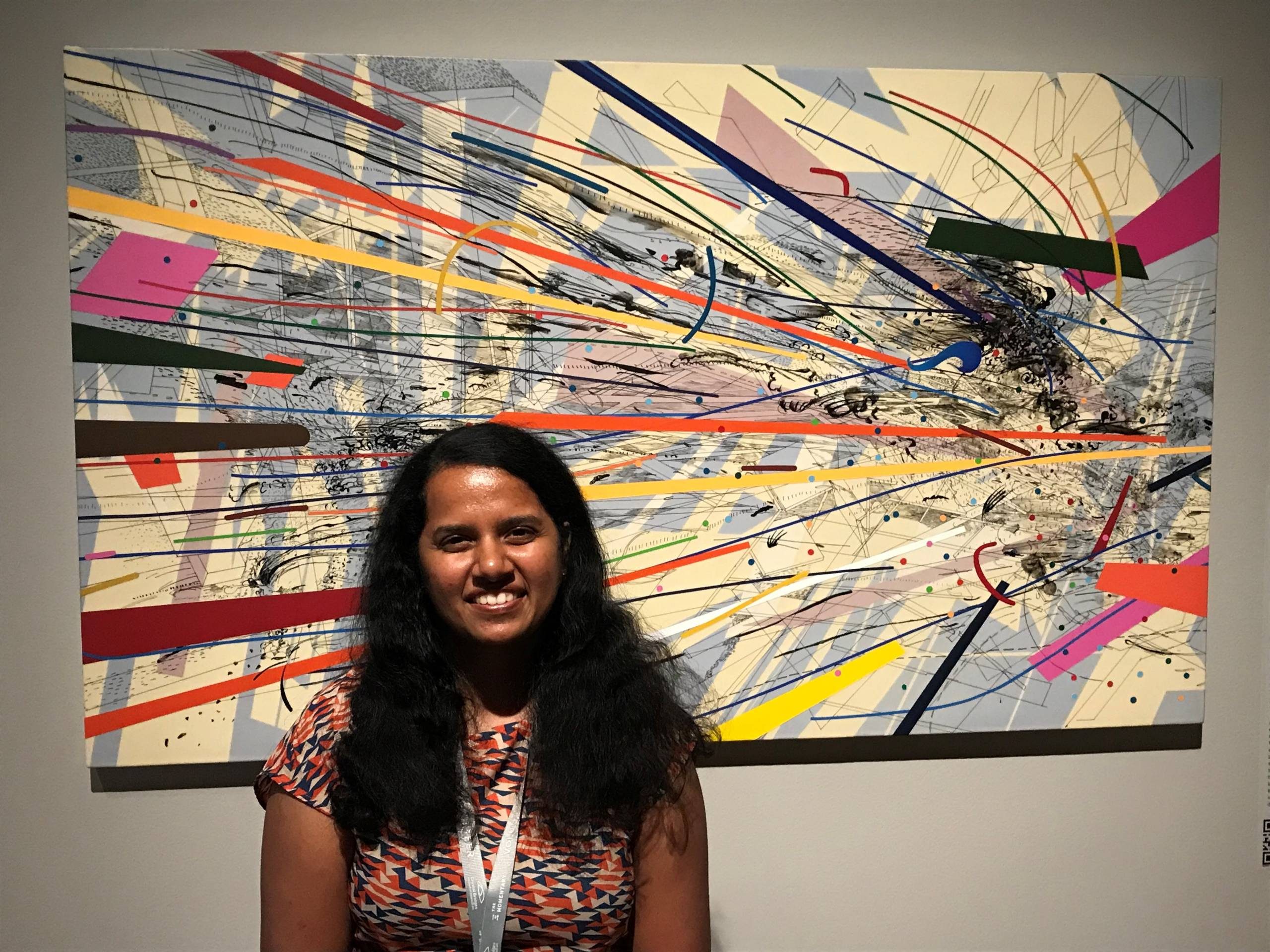 staff member aditee wadadekar stands in front of a work by julie mehretu
