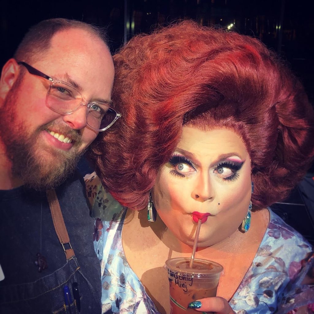 a staff member poses with drag queen Ginger Minj as she sips on a drink