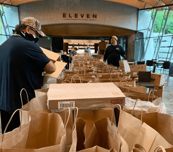 People packing paper bags and boxes in a venue called 