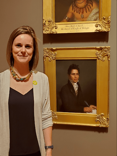 a visitor and ancestor of john ridge poses with his portrait in the galleries