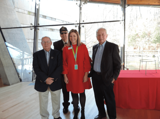 staff member poses with veteran volunteers in eleven